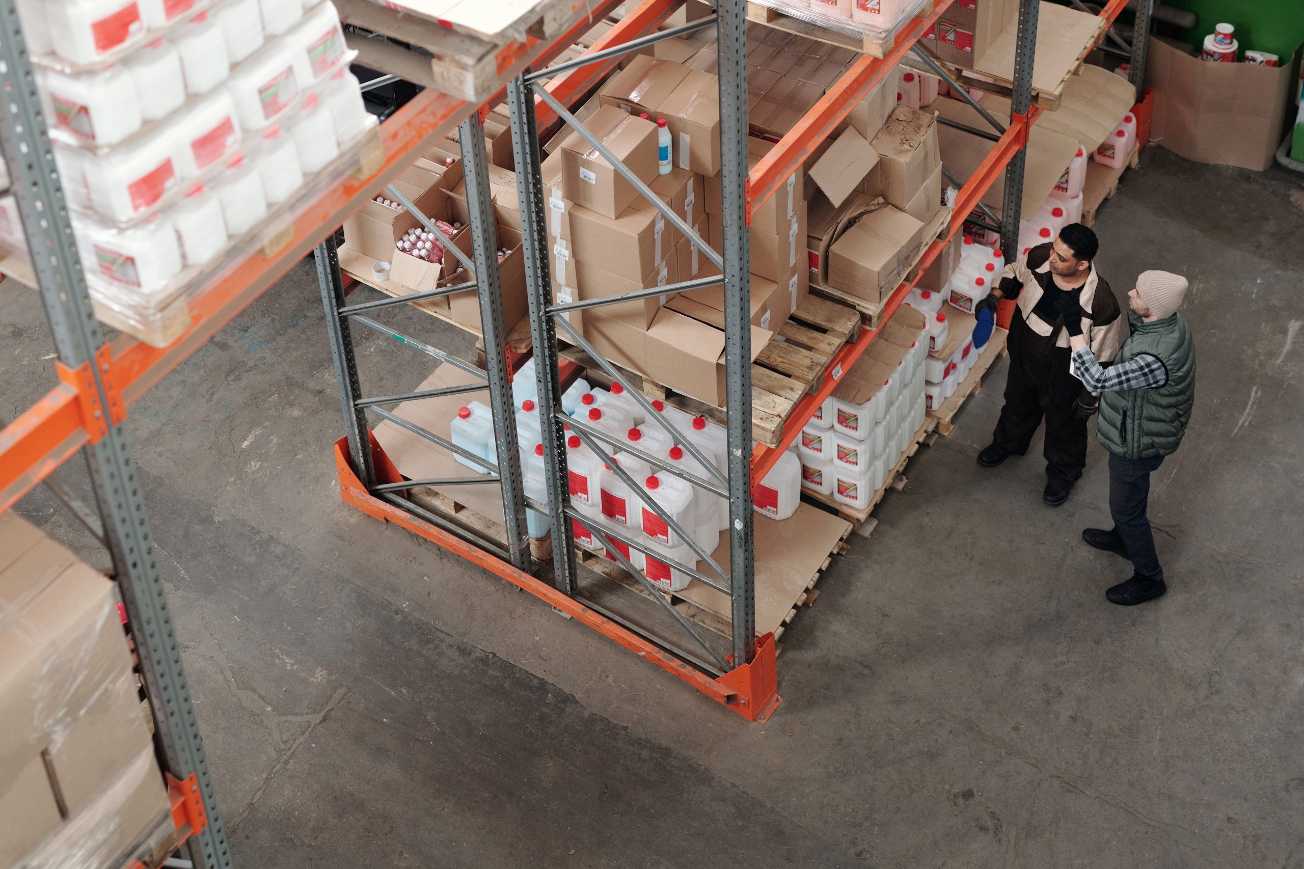 pexels photo 4481257 4481257 Two warehouse workers discussing logistics beside shelving with boxes and containers.